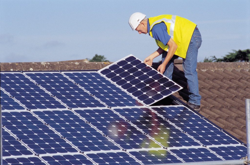 Un operario coloca paneles solares sobre un tejado.